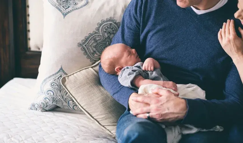 homme tenant dans ses bras un bébé 